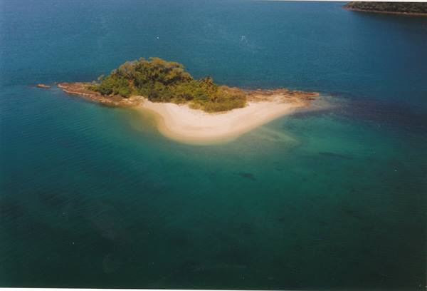 Small island with white sand beach and green vegetation surrounded by turquoise sea