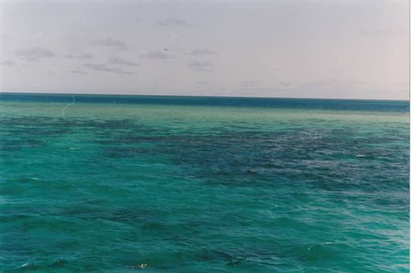 Turquoise sea water with submerged reef under a cloudy sky