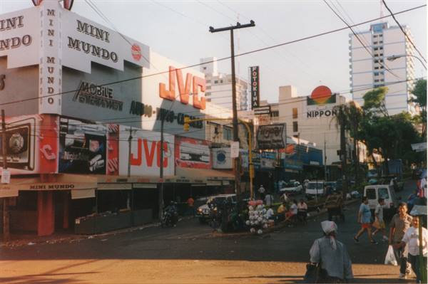 Pedestrians cross the intersection in front of JVC and Mini Mundo stores