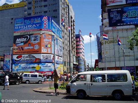 Busy Asunción intersection: vans, colorful billboard-covered buildings and Paraguayan flags