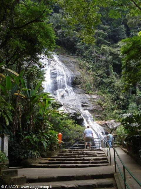 Waterfall in tropical forest, tourists climb the wet stone staircase