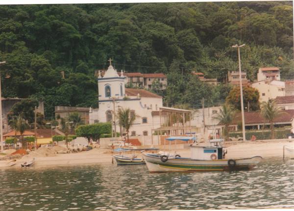 Fishing boats in front of the beach with white church and forested hill