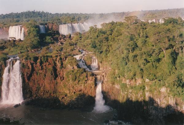 Iguazu Falls, red cliffs and green forest under sunlight