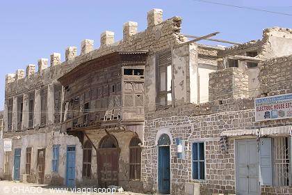 Coral-stone building with Ottoman wooden balconies under bright sunlight