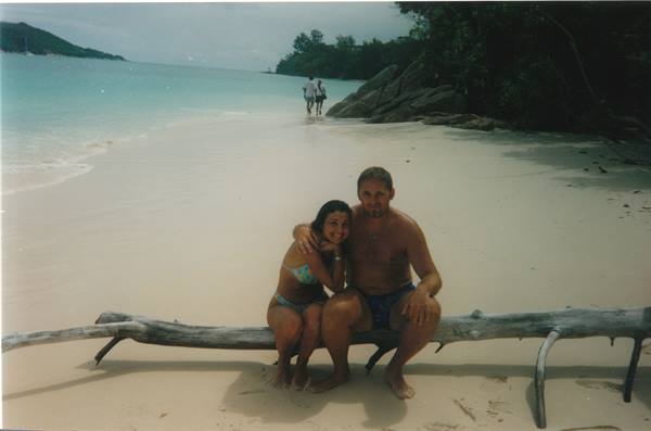 Couple sitting on driftwood log, tropical beach with white sand and turquoise water