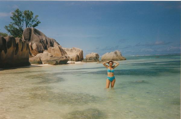 Woman in turquoise bikini wading among granite boulders, Anse Source d'Argent