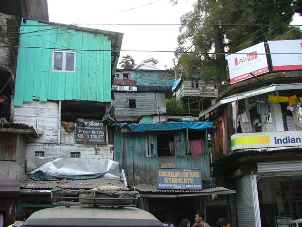 Wooden and tin houses in Darjeeling, Airtel signs, people below