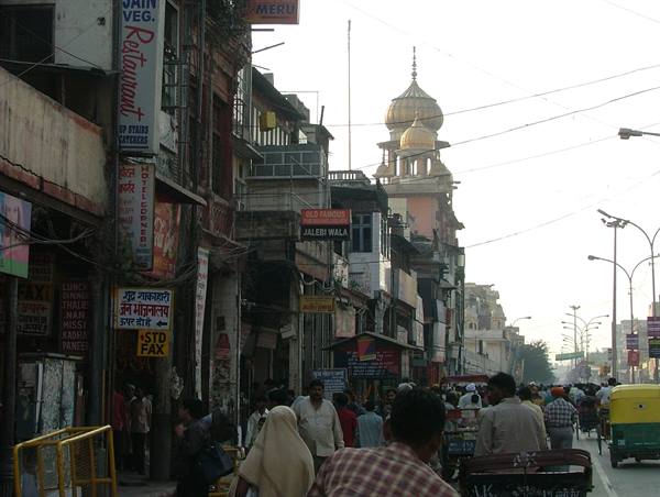 Crowded Chandni Chowk street in Delhi with the golden dome of Sis Ganj gurdwara