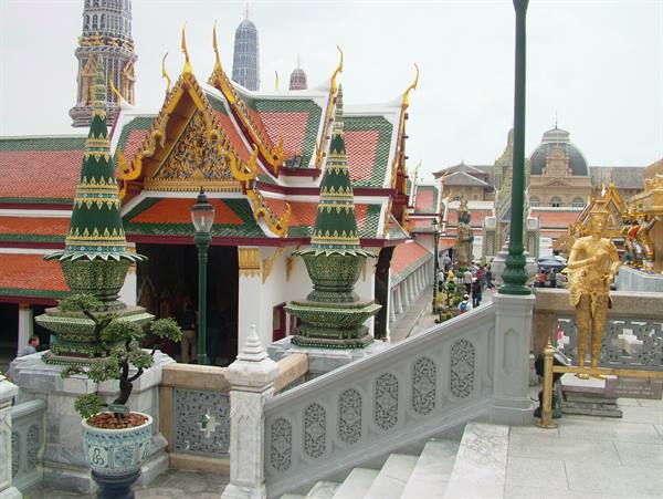 Wat Phra Kaew: glazed roofs, gilded chedi and statues along the staircase