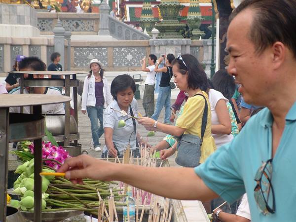 Worshippers offer incense and lotus flowers at Wat Pho temple, Bangkok