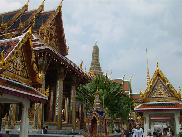 Wat Phra Kaew in Bangkok, golden roofs and visitors under a cloudy sky
