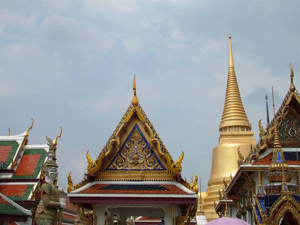 Wat Phra Kaew in Bangkok: golden stupa, ornate tiled roof and yak guardian statue