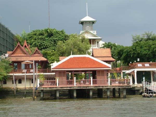 Wooden stilt pavilions by the river, red tiled roofs, cloudy sky