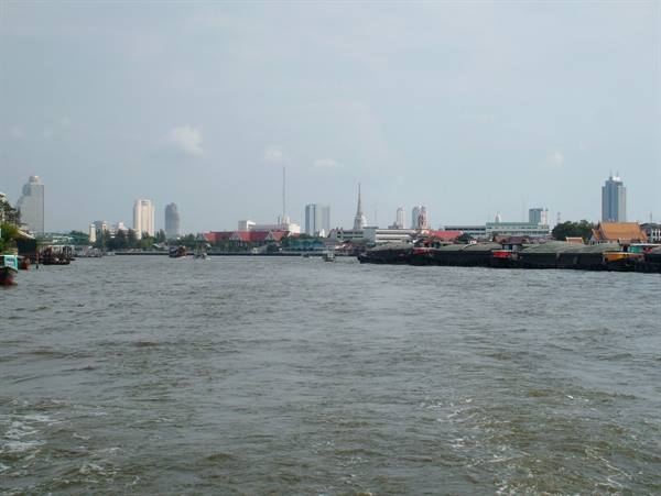 Chao Phraya river in Bangkok, grey sky, spires and skyscrapers across the water