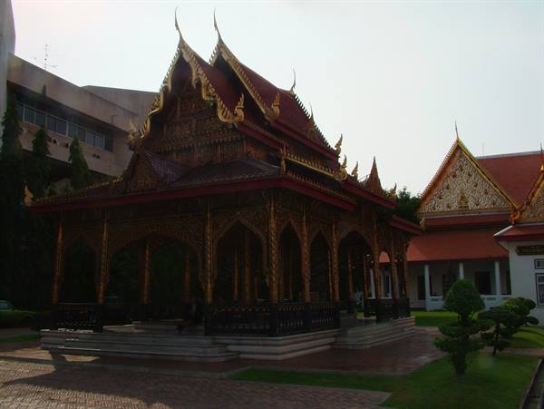 Gilded wooden Thai pavilion with pointed roofs in soft evening light