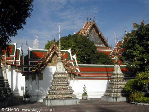 Wat Pho in Bangkok: decorated chedis, red and white roofs under the sun