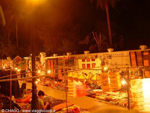 Luang Prabang night market, fabric stalls glowing under warm lamps