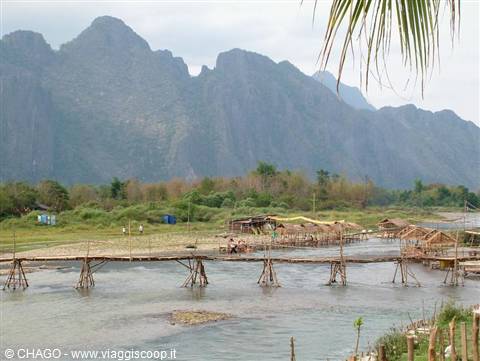 Bamboo bridge over the Song River in Vang Vieng, karst mountains behind