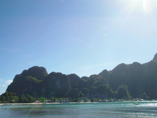 Limestone cliffs over El Nido bay, boats on turquoise water, bright sun