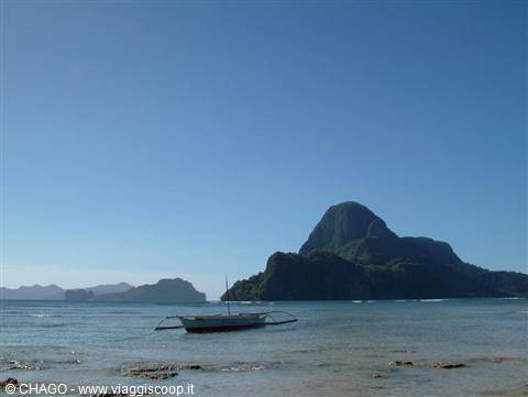 Filipino outrigger boat resting on the shore of El Nido before limestone mountains