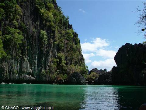 Turquoise water beneath limestone cliffs covered in tropical vegetation