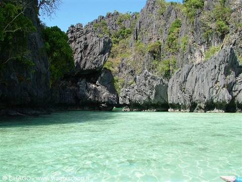 Turquoise lagoon beneath limestone cliffs and greenery, El Nido