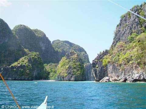 Boat bow approaching green limestone cliffs in El Nido, Palawan