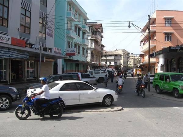 City intersection with cars, motorcycles and green jeep among colorful buildings