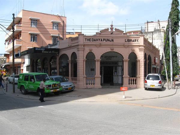 The Dahya Punja Library, pink arched building, cars and pedestrian on the street