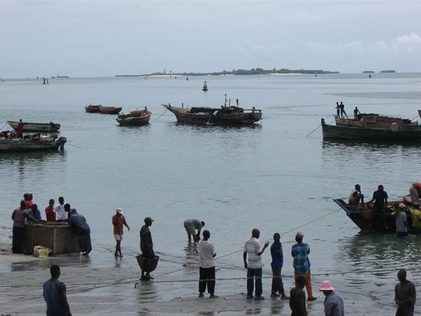 Fishermen and wooden boats on the shore of Stone Town harbor, Zanzibar