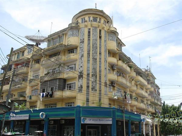 Yellow colonial building with curved balconies, tangled power lines and bank signs below
