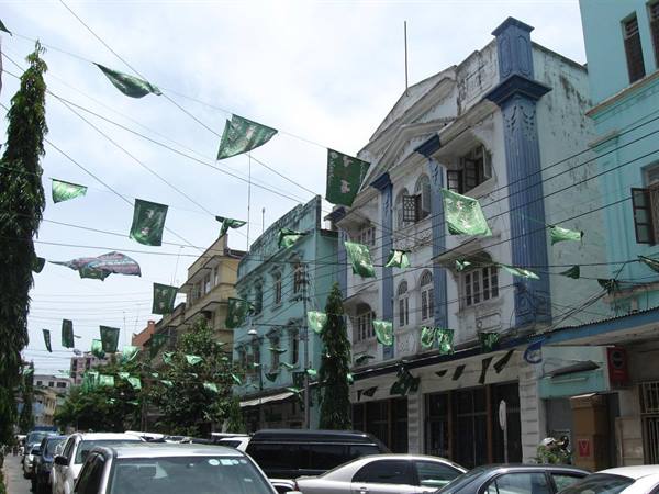 Green flags strung across colonial buildings and traffic in Yangon