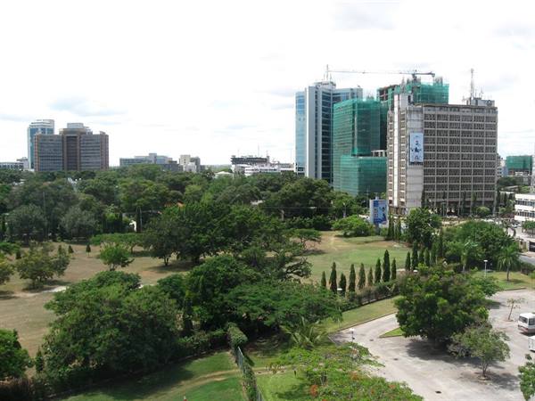 High-rise buildings behind city park trees under a cloudy sky