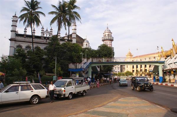 White mosque with minarets among palms, pedestrian bridge and traffic in Yangon