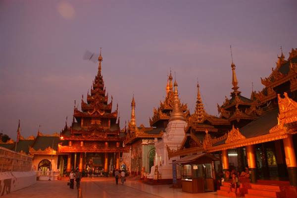 Golden pavilions and white stupa at Shwedagon Pagoda at dusk