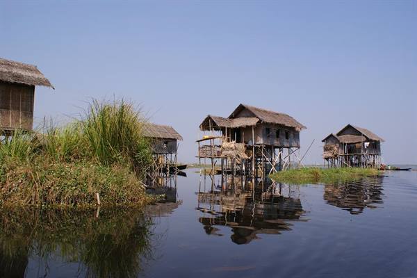Wooden stilt houses on Inle Lake, reflected in the calm water