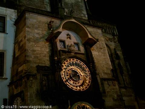 Medieval astronomical clock illuminated at night on the stone town hall facade