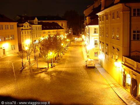 Hradčany Square at night in Prague, wet cobblestones glowing under streetlights