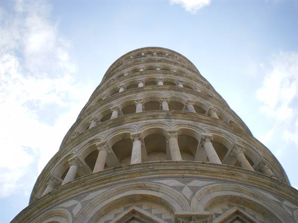 Leaning Tower of Pisa from below: white marble loggias against a cloudy sky