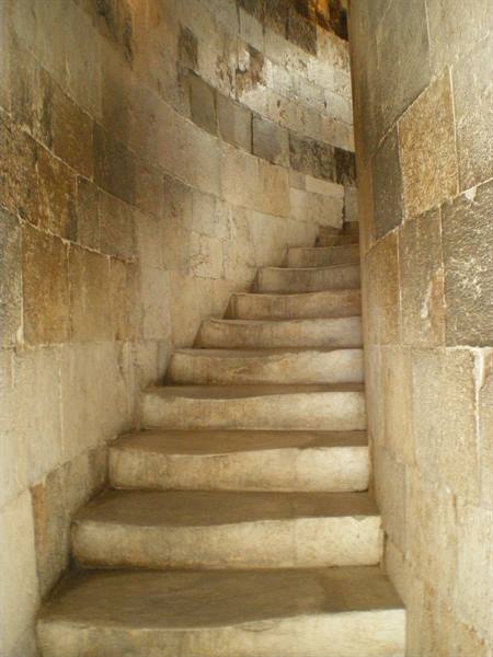 Worn marble spiral staircase, warm light on stone walls