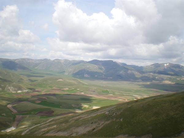 Castelluccio plateau: patchwork fields between green mountains and clouds
