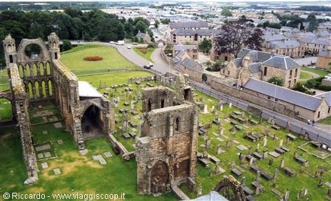 Stone ruins of Elgin Cathedral among gravestones and grey slate rooftops
