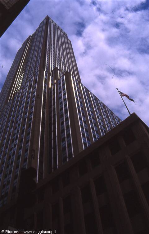 Stone skyscraper against clouds, American flag on rooftop, New York