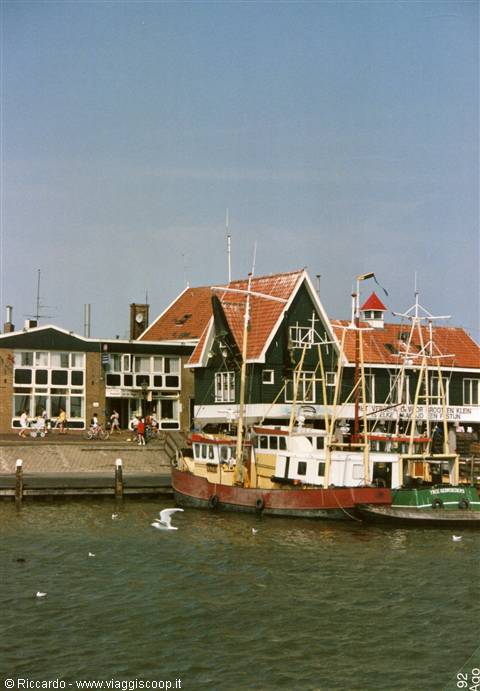 Fishing boats moored at Volendam harbor in front of green wooden houses