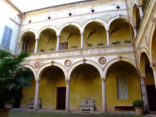 Renaissance courtyard with double arched loggia, yellow walls and palm