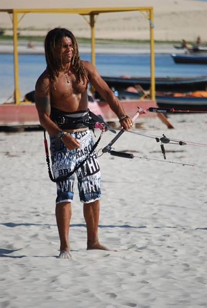 Kitesurfer with dreadlocks prepares his gear on the sand in Jericoacoara