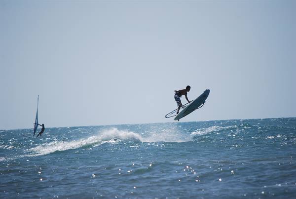 Windsurfer mid-air jumping over waves while another sails nearby