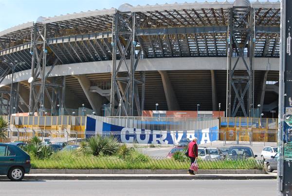 Woman walks past Maradona stadium with CURVA A banner in Naples