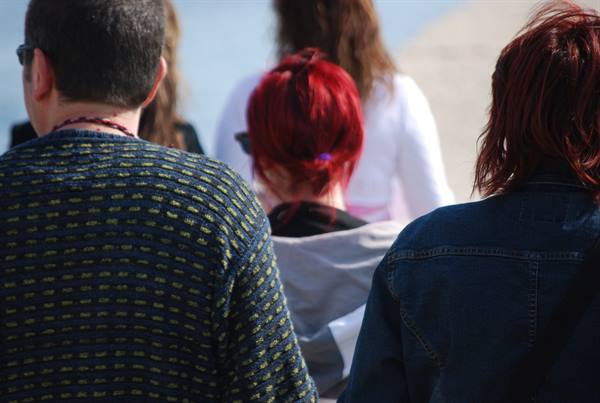 People seen from behind, man in blue patterned sweater, woman with red hair