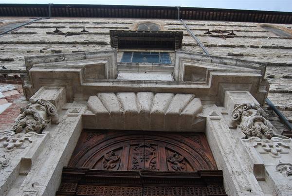 Stone portal with carved grotesque masks and ornate wooden door, historic palace